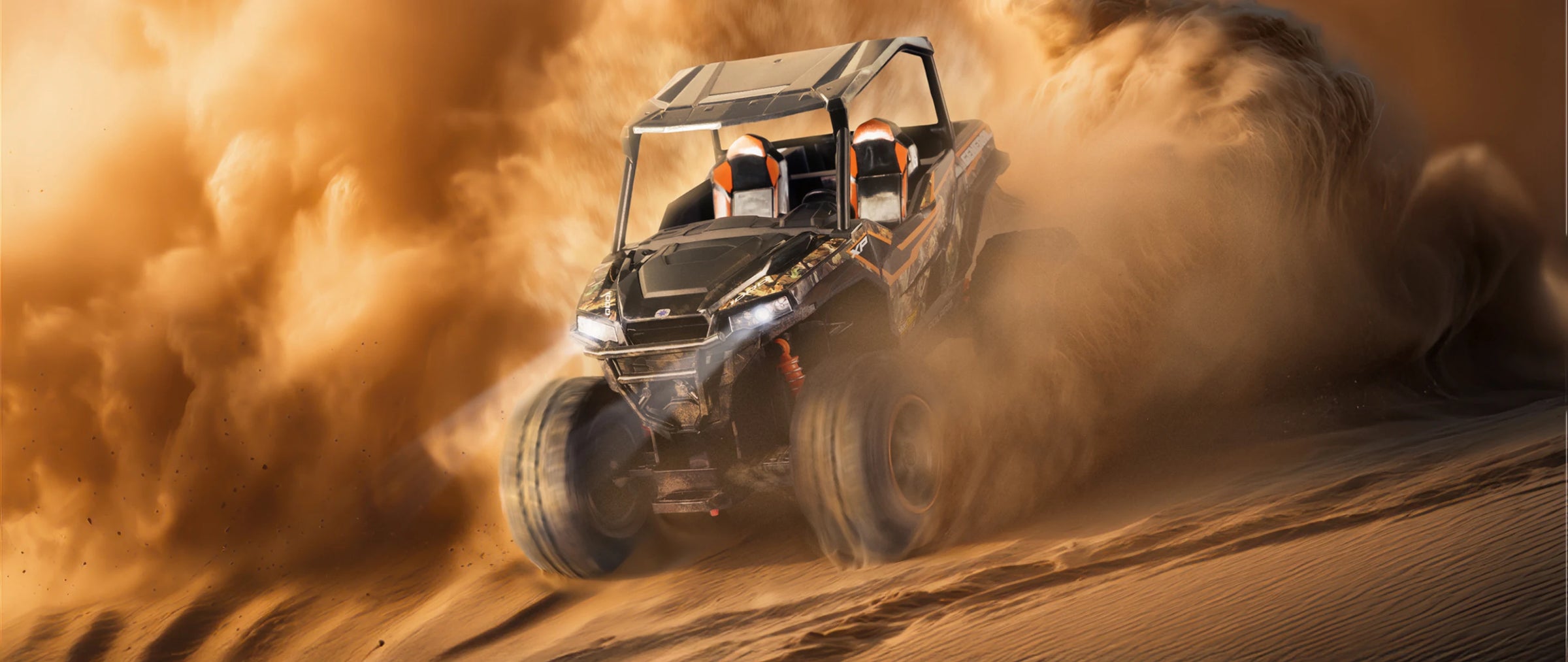 Off-road vehicle driving through sand with dust in the air