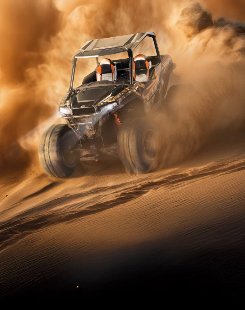 Dune buggy driving through sand dunes with dust in the air